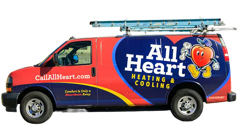 A heating and cooling service van with a heart mascot, large “All Heart Heating & Cooling” text, a ladder on top, and the website CallAllHeart.com on the side.